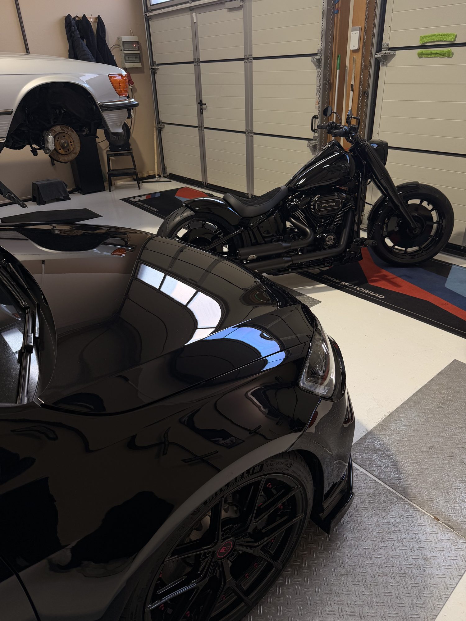 Schwarzes Auto und schwarze Harley nebeneinander im Detailing-Studio